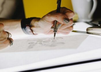 person lettering on tracing paper using mechanical pencil
